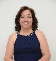 ¡Adiós, Regina Prospero! Una mujer elegantemente vestida con vestido azul, sentada y bien arreglada.