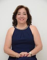 ¡Adiós, Regina Prospero! Una mujer elegantemente vestida con vestido azul, sentada y bien arreglada.